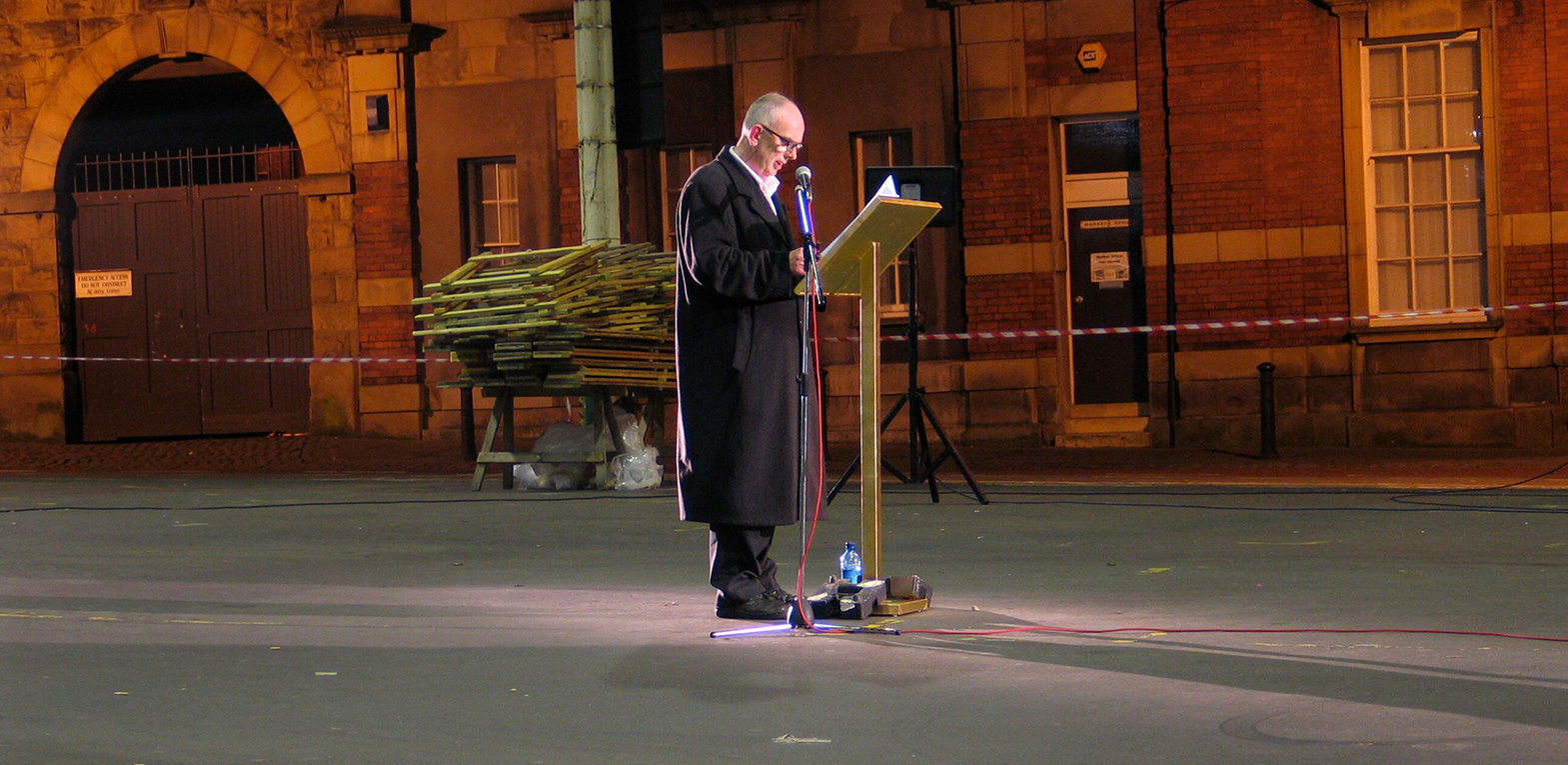 The Preston Market Mystery Project. The artist John Newling delivers a speech while standing at a podium.