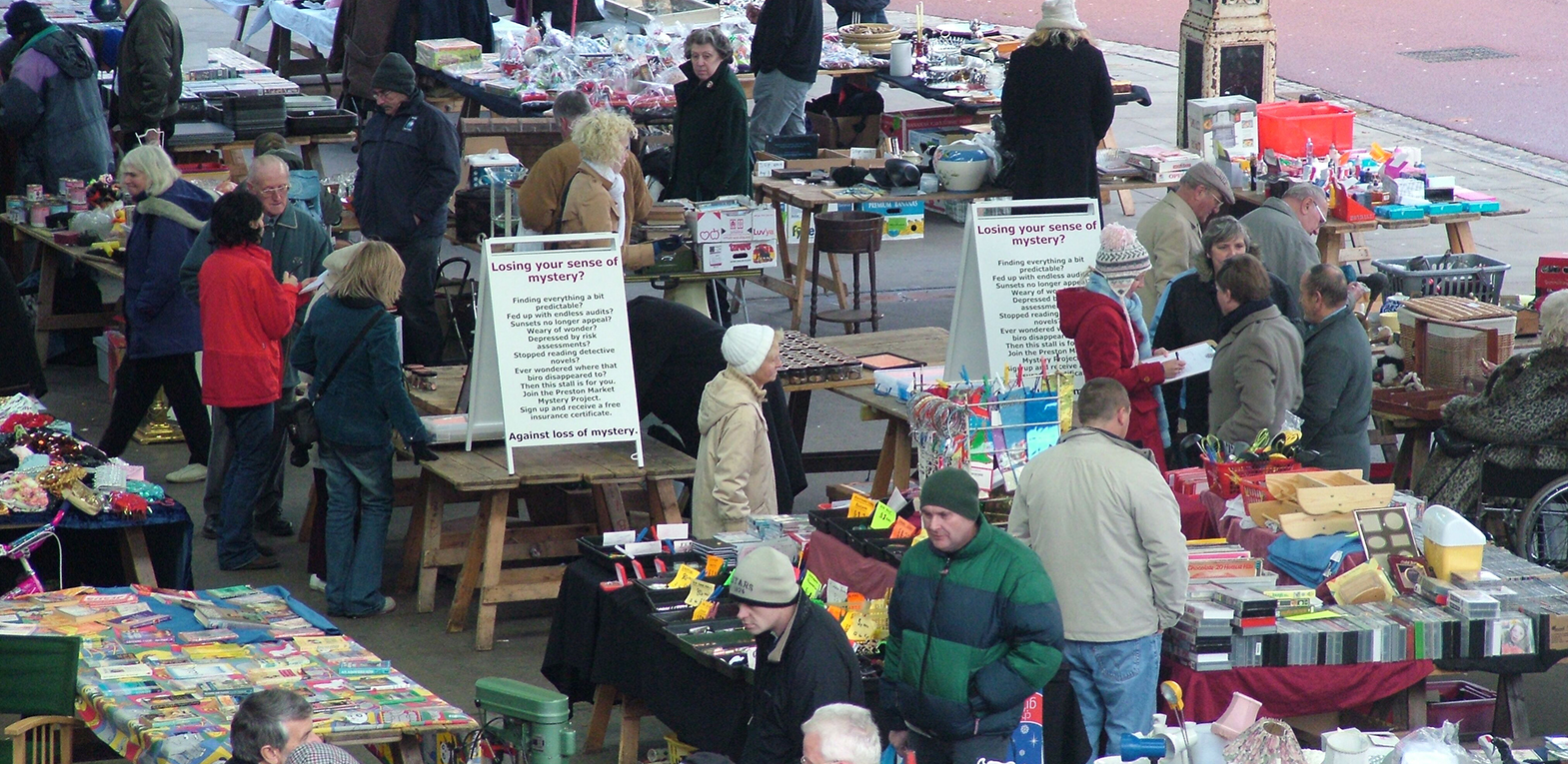 Signs advertising The Preston Market Mystery Project on display at a buy car boot at Preston Market.