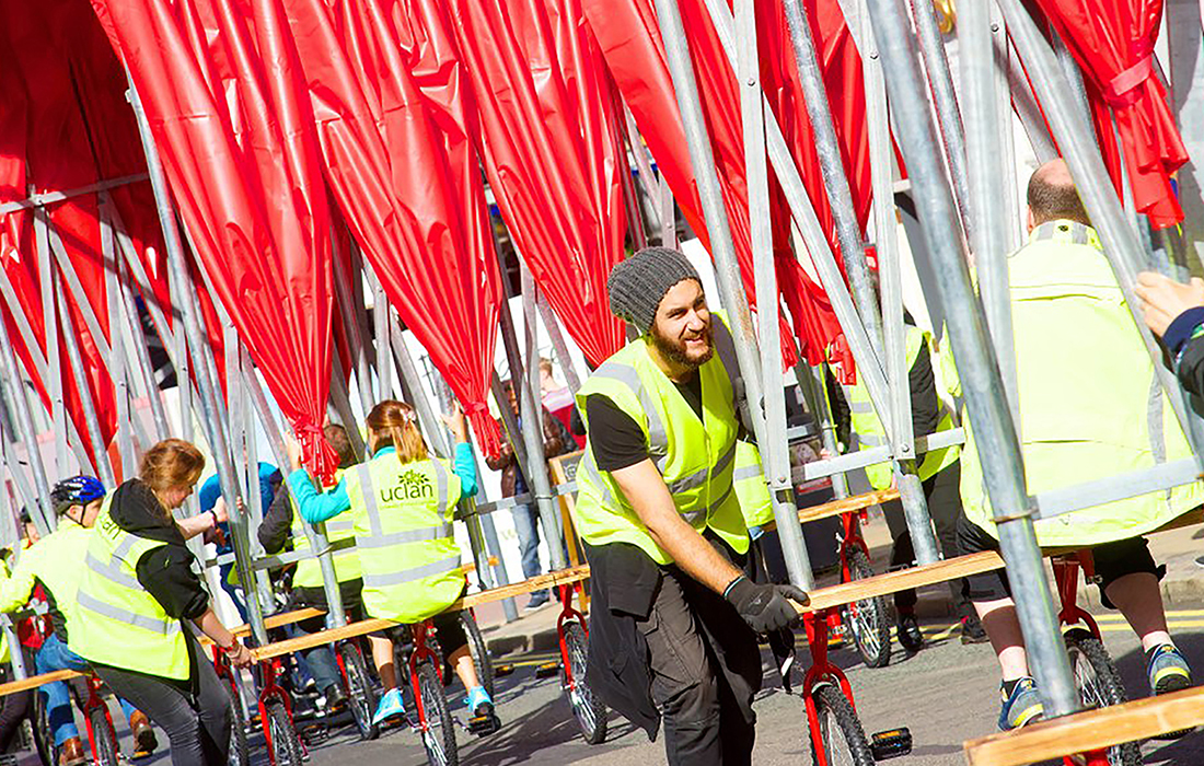 A team of volunteers in hi-viz pedal the The People's Canopy from the UCLan campus to the Harris Square in Preston