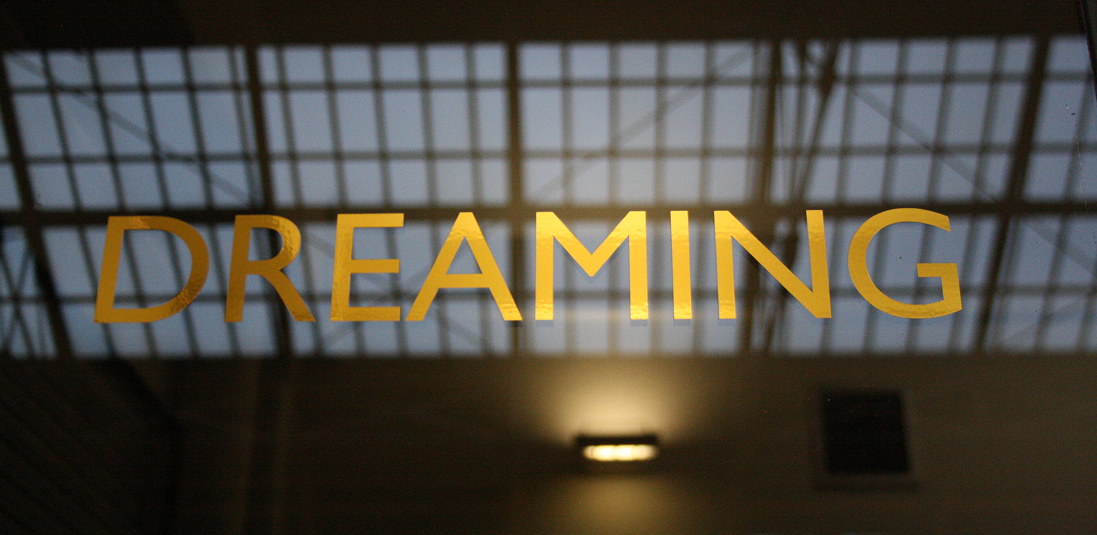 Letters on the windows of the waiting rooms of Preston train station as part of an artwork by Lisa Wigham. The word is 'dreaming'.