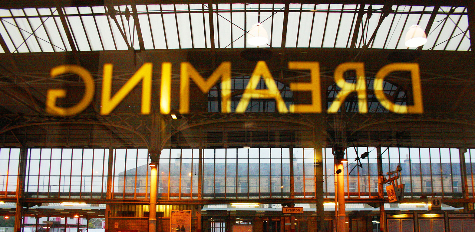 Letters on the windows of the waiting rooms of Preston train station as part of an artwork by Lisa Wigham. The word is 'dreaming' and is photographed from behind